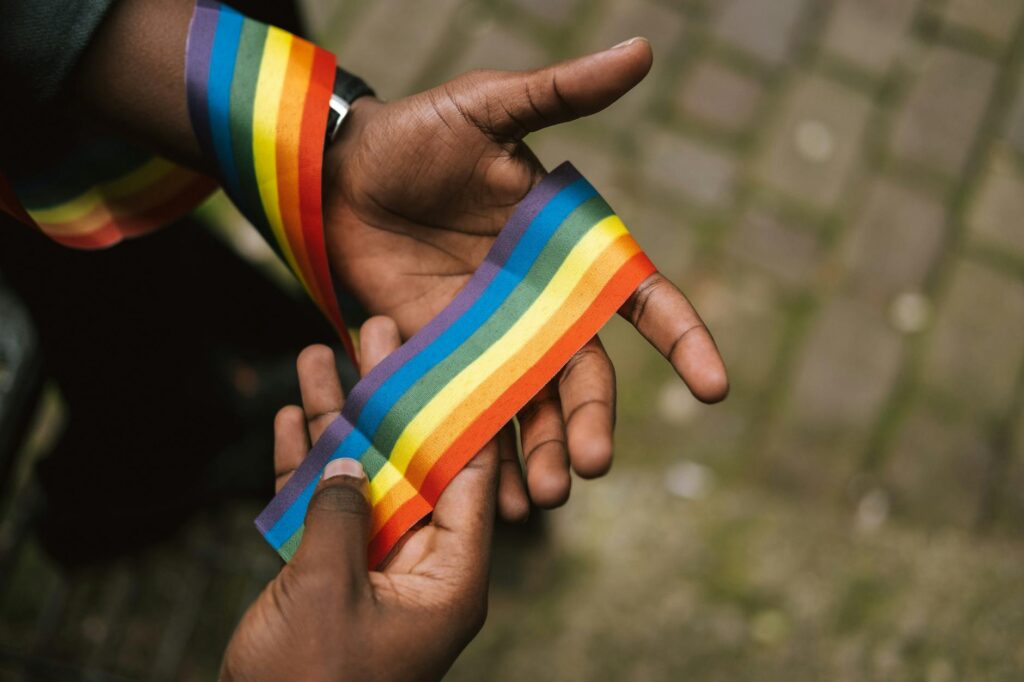 D'en haut, récoltez des gays afro-américains démontrant un ruban arc-en-ciel coloré à portée de main contre un trottoir pavé