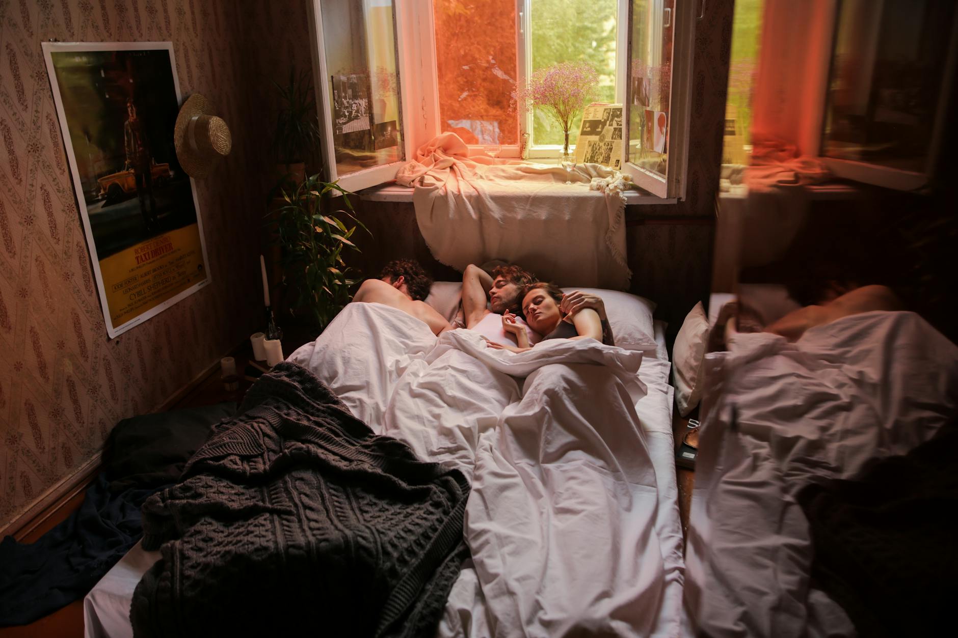 Trois personnes endormies dans une pièce chaleureusement éclairée, capturant une tranquillité intime.